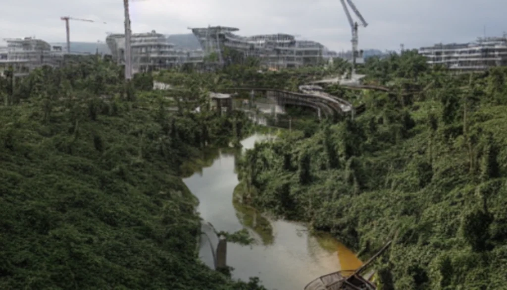 Baustelle der neuen Hauptstadt Nusantara auf Borneo, mit großen Maschinen, halbfertigen Gebäuden und abgeholztem Regenwald im Hintergrund